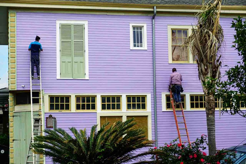 Dos hombres haciendo una reforma en una casa, pintando las paredes exteriores